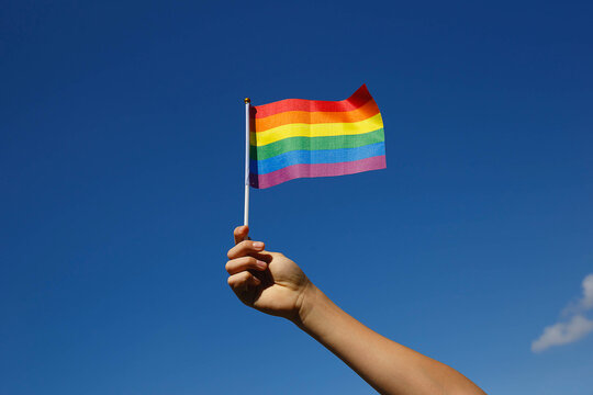 Small Lgbt Flag In The Hand Against The Blue Sky