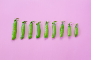 Green peas on a pink background. View from above. Pop art design, creative concept of summer food....