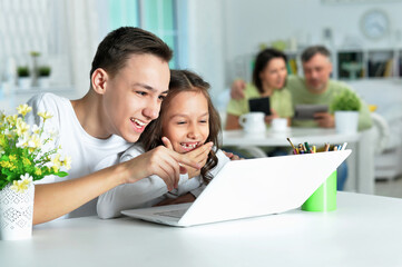 brother and sister using laptop while sitting at table