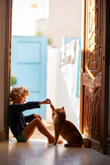 The boy feeds the cat at home - 438406167