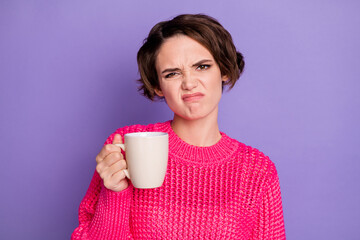 Photo of young girl displeased unhappy grimacing bad smell hold cup of tea isolated over purple...
