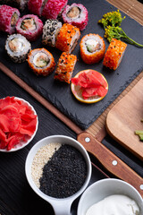 Fototapeta na wymiar sushi set with ingredients served at black dish at black table. flat lay