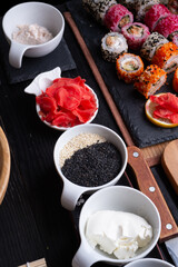sushi cooking set with rice and ingredients served at black dish at black table. flat lay