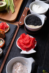sushi cooking set with rice and ingredients served at black dish at black table. flat lay