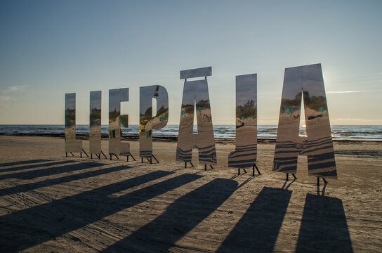 Liepaja city title at Baltic beach. Big mirroring letters in sunny evening. 
