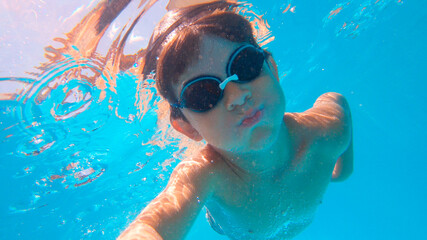 Naklejka premium Portrait of Underwater Young Boy Fun in the Swimming Pool with Goggles. Summer Vacation Fun.