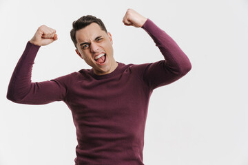 Young brunette man screaming and making winner gesture