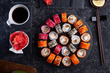 different sushi rolls set  with fish and  shiitake mushrooms  served  at black dish with rise at black table. flat lay
