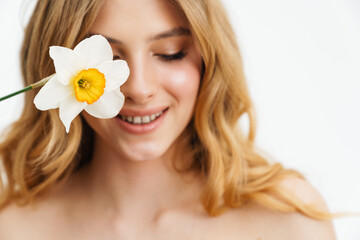Obraz na płótnie Canvas Half-naked blonde woman smiling while posing with daffodil