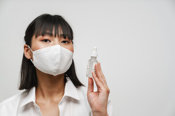 Young asian woman in face mask showing facial serum