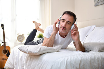 Music lover man listened concentrated lying on the bed