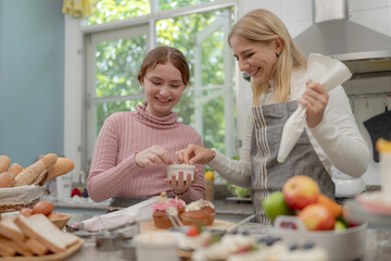 Mother and daughter preparing tasty food and bakery at kitchen. Mommy teaching daughter to cook.
