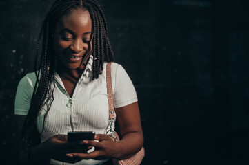 Cheerful african american woman using smartphone while in a subway