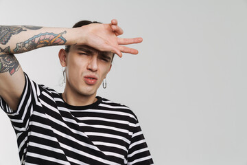 Young white man with earring frowning and gesturing at camera