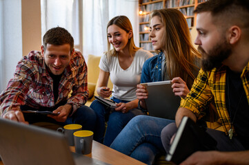 A group of young students using laptop and digital tablet while studying at home
