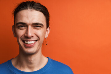 Young white man with earring looking and laughing at camera