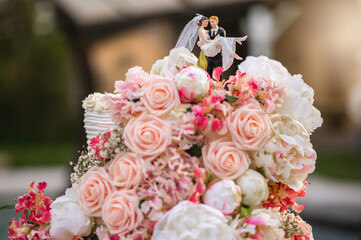 Wedding cake with flowers decoration and couple on the top.