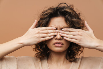 Young curly hispanic woman posing and covering her mouth