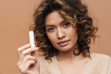 Obraz premium Young hispanic curly woman posing and showing lipstick