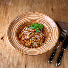 Pasta udon noodles- with beef and vegetables on a plate On a wooden surface.