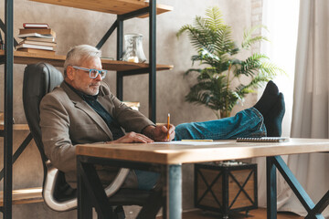 Reluctance to work. Senior man businessman sits with his legs thrown on the table. Loss of energy,...