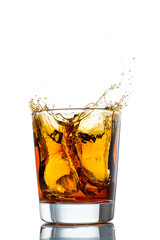 splash in glass with whiskey from falling ice on white background isolated