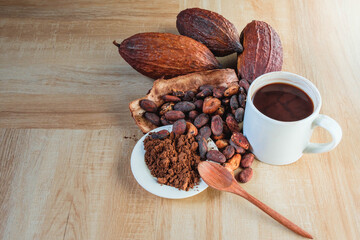 Hot cocoa cup with cocoa powder and cocoa beans on wooden background