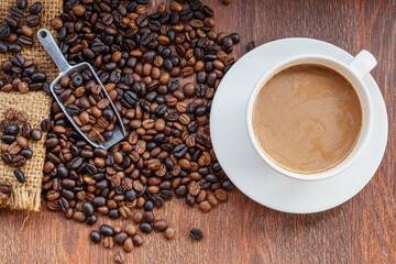 cup of coffee and coffee beans in a sack on  Brown background, top view