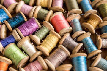 The background is made of colorful threads on wooden vintage reels. Skeins of colored thread. Top...