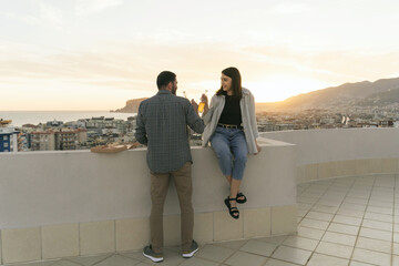 Couple enjoying seascape, on the rooftop. Happy people spend quarantine time, picnic leisure on the roof and watch the city view.