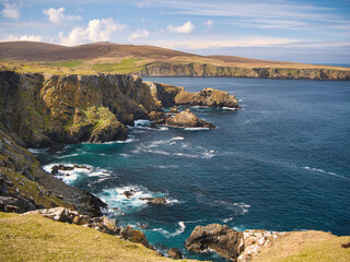 Sea cliffs and turquoise water around Clibberswick on the island of Unst in Shetland, UK - these rocks are part of the geologically significant Shetland Ophiolite Complex - Metaharzburgite