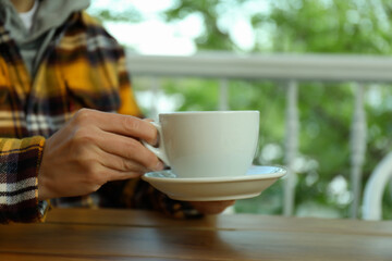 Woman holds saucer with cup of hot drink, close up
