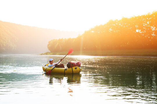 Tourist on yellow packraft rubber boat with red padle