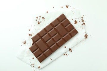 Tasty chocolate bar on paper on white background