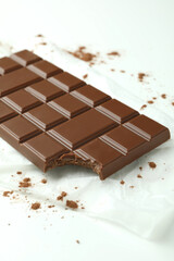 Tasty chocolate bar on paper on white background