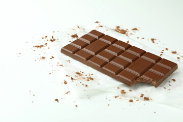 Tasty chocolate bar on paper on white background