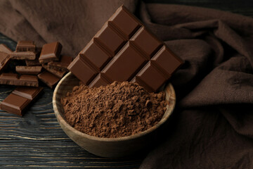 Tasty chocolate bars and powder on wooden table