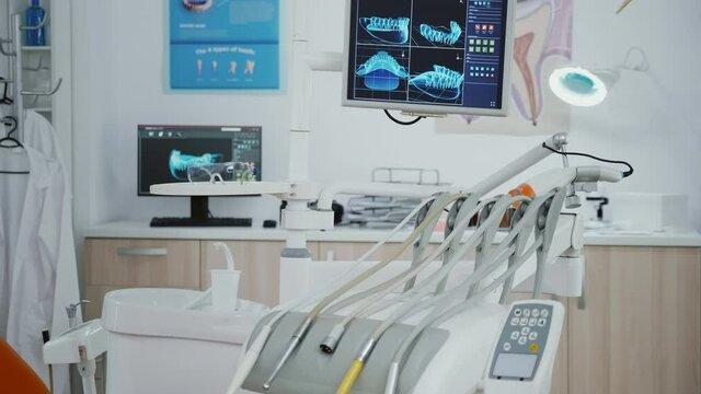 Closeup revealing shot of medical orthodontic display with teeth xray images on it. Stomatology dental chair with nobody in it equipped with dentistry tools prepared for orthodontic healthcare surgery