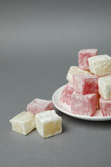 Plate with delicious turkish delight on gray background