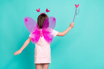 Photo of sweet carefree schoolgirl dressed pink overall wings holding fairy wand isolated turquoise...