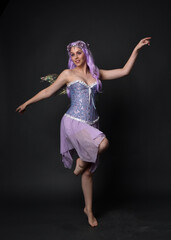 Full length portrait of a purple haired  girl wearing fantasy corset dress with fairy wings and...