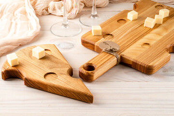 Cutting board made of light wood with cheese-like holes on a dark wooden background