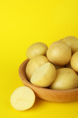 Bowl of young potato on yellow background
