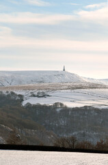 snow covered fields with stoodley pike monument and moors in the distance in calderdale west yorkshire