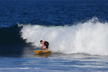 Fototapeta na wymiar Surfers ride the waves in Bali, Indonesia during summer vacation
