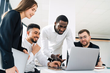 Group of multiracial white collar workers in the office behind a laptop