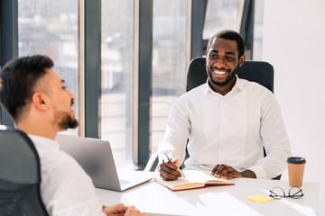 Business colleagues talking while sitting at the table in the office