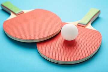 Ping pong rackets and ball on blue background