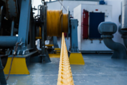 Marine hydraulic winch for mooring operations with yellow ropes wound around it.