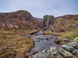 Fototapeta na wymiar On an overcast, rainy day, the stream from Mill Loch on Muckle Roe, Shetland, UK